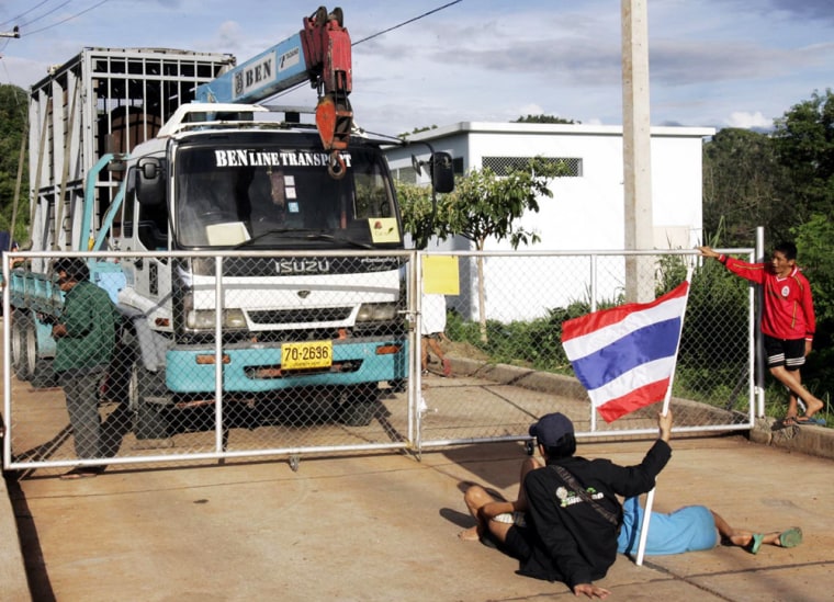 Thai activists block the gate of Mahidol University's Livestock and Wildlife hospital in Kanchanaburi province, southwestern Thailand as a truck carrying an elephant stops on the other side during a protest against the transfer of elephants to Australia Tuesday, June 6, 2006. The transfer of eight Asian elephants to Australia zoos was in limbo Tuesday after animal rights activists prevented trucks from carrying the animals to the airport, arguing that they would suffer abroad. (AP Photo/Apichart Weerawong)