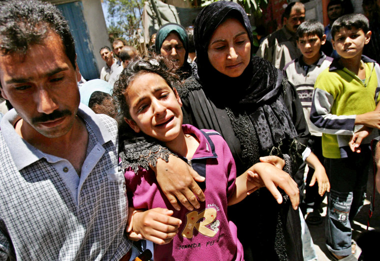 Palestinian girl Houda Ghalia, center, is comforted during the funeral for her parents and siblings in Beit Lahiya, in the northern Gaza Strip, Saturday, June 10, 2006. They were killed by an Israeli army artillery shell while on beach pinic Friday and Palestinian officials said seven people were killed and more than 30 wounded in the attack with the Ghalia family losing six members, among them the father, one of his two wives, an infant boy and an 18-month-old girl. The Israeli army said it had targeted areas in the northern Gaza Strip used by Palestinian militants to fire homemade rockets at Israel. (AP Photo/Kevin Frayer)