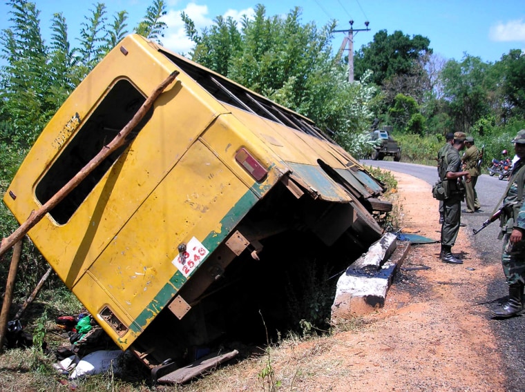 Soldiers patrol near a bus overturned by a landmine blast in Kabithigollewa, about 210 kilometers (131 miles) northeast of Colombo, Sri Lanka, Thursday, June 15, 2006. Sri Lanka's air force bombed Tamil rebel-held areas in the northeast on Thursday, after a powerful mine blast ripped through a bus packed with commuters and school children, killing at least 62 people, the army said. (AP Photo/Bandula Senaviratna)