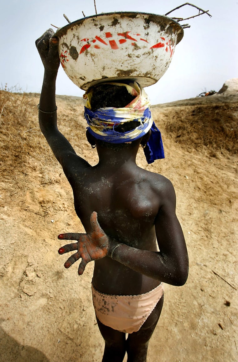 Madelaine Dog, 8, carries excavated earth from a salt mine hole on Senegal's coastline