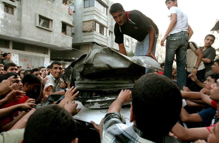 Palestinians inspect the wreckage of a car after it was hit by an Israeli missile strike at the Jebaliya refugee camp Tuesday June 20, 2006. Israeli aircraft fired missiles at the car killing two children and wounding 9 others, the military and hospital officials said. The Israeli military said the car was carrying militants from the Al Aqsa martyrs' Brigades, affiliated with President Mahmoud Abbas' Fatah movement. Among the wounded were five children. (AP Photo/Petros Karadjias)