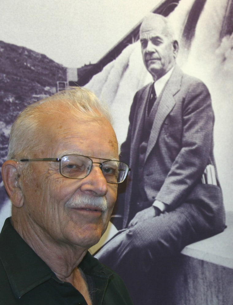 Wilfred Woods with a painting of his father, Rufus, a legendary newspaper publisher in Washington State who pushed for the building of Grand Coulee Dam. Now the Woods family is worried that new data centers build by Microsoft and others will exploit cheap hydroelectricity while creating too few jobs. 