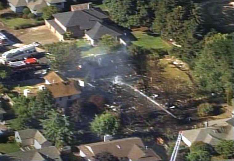 Firefighters spray water over the wreckage of the airplane which crashed into the Hillsboro neighborhood.
