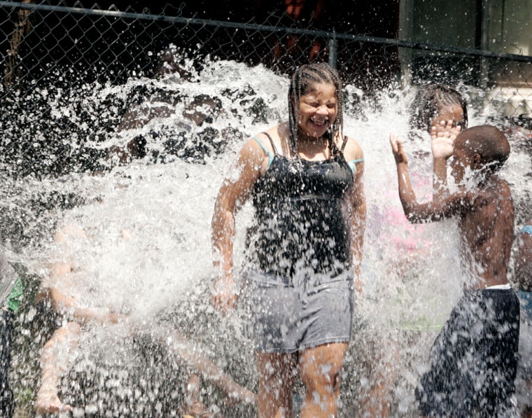 Kids enjoy the cooling waters from a fire hydrant in St. Louis on Monday.  
