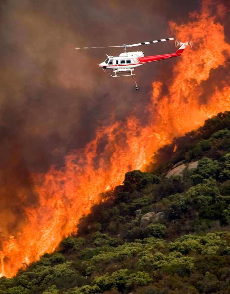 Helicopter flies past flames during wildfire in San Diego