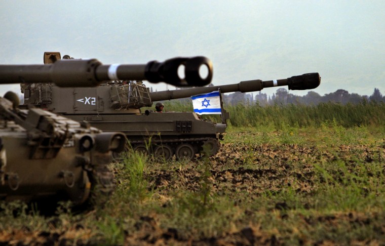 Israeli army artillery move through a field near Kibbutz Kfar Sald, northern Israel, near the border with Lebanon, on Monday.