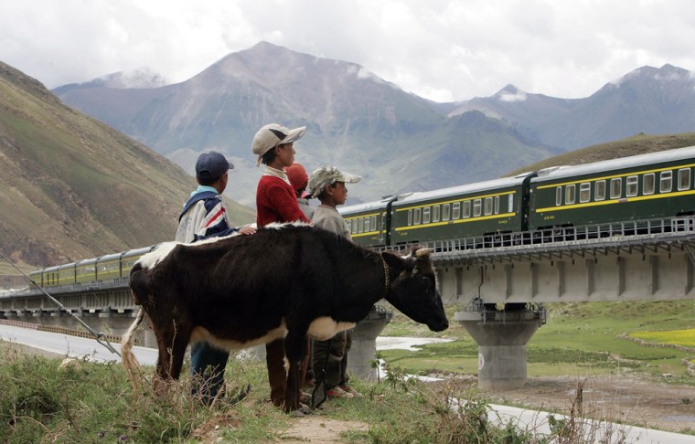Tibetan children watch as the first train from Lhasa Railway Station travels on the Tibetan grasslands near Lhasa, Tibet, on July 1.
