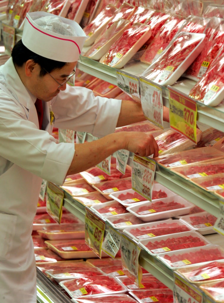 An employee puts packs of Australian beef on the shelf in Tokyo. Japanese officials have ended a ban on U.S. beef imposed in January due to concerns about mad cow disease.