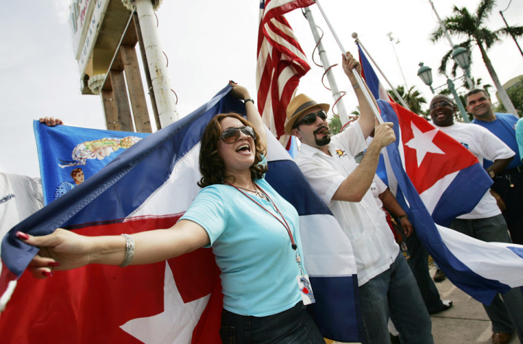 Cubans wave Cuban and US flags as they c