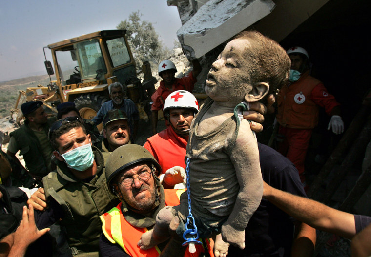 ** EDS NOTE GRAPHIC CONTENT ** Lebanese Red Cross and Civil Defense workers carry the body of a small child covered in dust from the rubble of his home that was hit in an Israeli missile strike in the village of Qana, east of the port city of Tyre, Lebanon Sunday, July 30, 2006. Lebanese Red Cross officials said 56 people died in the Israeli assault on the village, including 34 children. Rescuers dug through the debris to remove dozens of bodies. (AP Photo/Kevin Frayer)