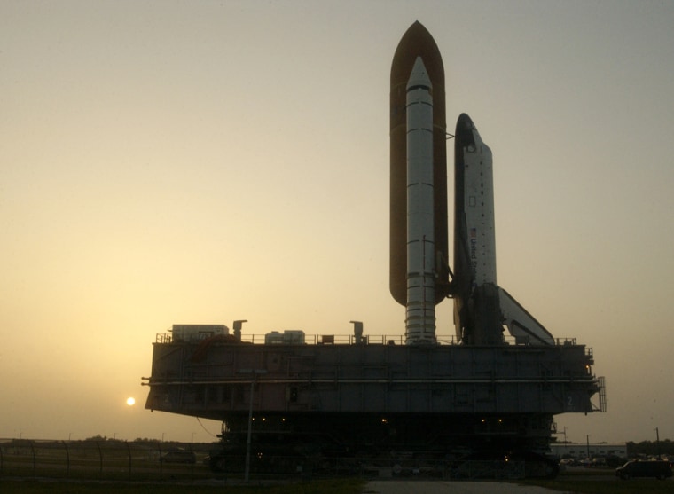 The sun rises behind the US space shuttl