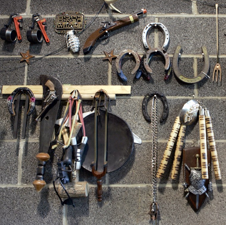 A fake hand grenade, toy gun, machete and other items seized at airport security checkpoints hang on the "wall of fame" at the Pennsylvania General Services Department's surplus property program warehouse in Harrisburg on Aug. 11.