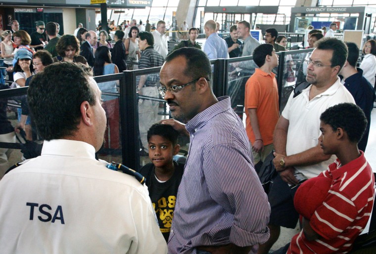 TSA officer Larry Morgan, left, speaks with Mo Osman of Washington, D.C., and his 9-year-old son Khalil Osman, second from left, during a security check at Dulles International Airport.