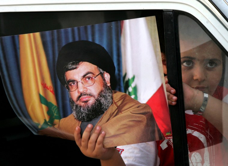 A Lebanese girl holds a picture of Hezbollah leader Sheik Hassan Nasrallah on Monday as she heads back to south Lebanon with her family on a damaged section of road near Naami, south of Beirut.