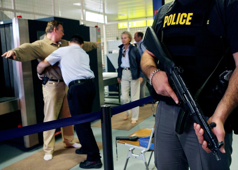 An armed Swiss police officer, right, stands guard next to a security person who frisks a passenger at a security checkpoint at a boarding gate for a flight to New York, at Geneva International Airport, Switzerland, Tuesday Aug. 15, 2006. (AP Photo/Keystone, Salvatore Di Nolfi)