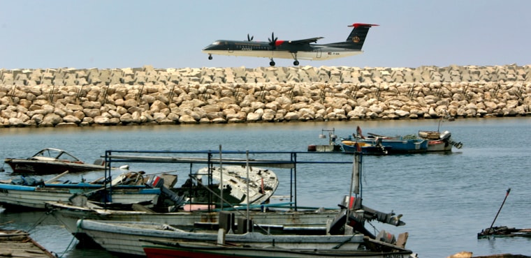 A Royal Jordanian airliner passenger jet lands in front of several destroyed fishing boats, which were targeted by Israeli bombardment during the war with Hezbollah, at Beirut airport, Lebanon, on Thursday. A Middle East Airlines passenger jet from Amman, Jordan, marked the first commercial flight to fly to Rafik Hariri International Airport since July 13.
