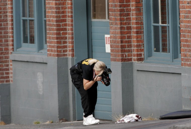 Unidentified crime scene investigator photographs evidence in front of The Jewish Federation building in downtown Seattle