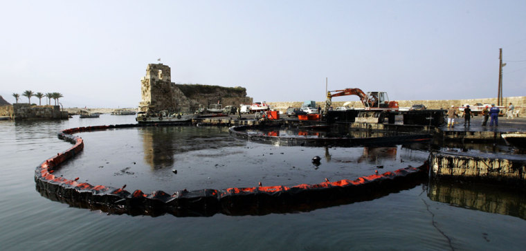Workers from Byblos town council clean up an oil spill at the harbour of the ancient Phoenician city in central Lebanon