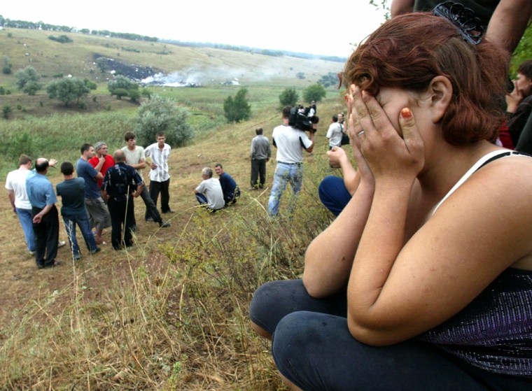People grieve near the crash site of a Russian Tupolev Tu-154 airplane