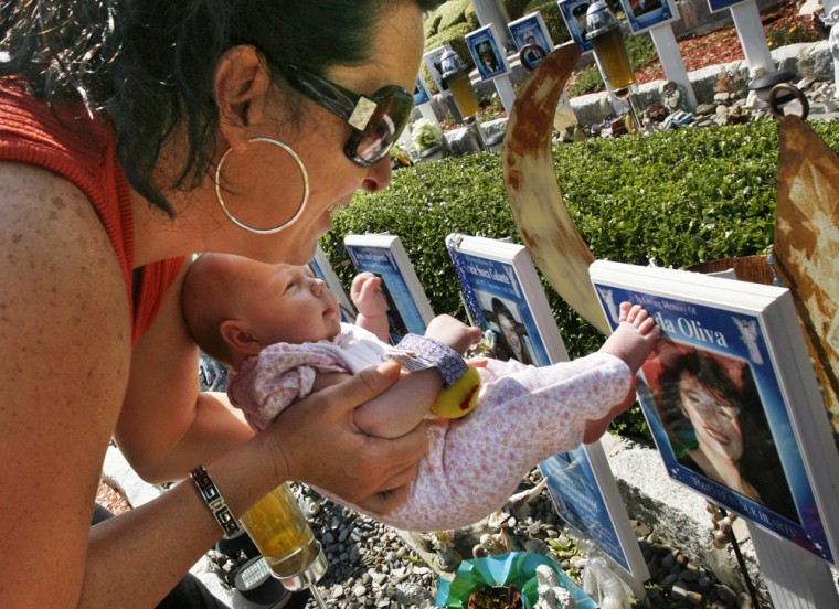 Bonnie Lakatos holds her six-week old daughter, Alexandria, with her toes touching the picture of her close friend Linda Olivia at the Angels Circle Memorial on July 24, 2006, in the Staten Island borough of New York. Olivia died on Sept. 11 during the attacks on the World Trade Center towers. (AP Photo/Kathy Willens)