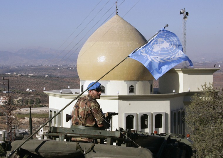 An Italian U.N. peacekeeper is seen atop an armored personnel carrier with a U.N flag on Sunday, as he drives past Kalaway Mosque in a convoy to a new camp in south Lebanon.