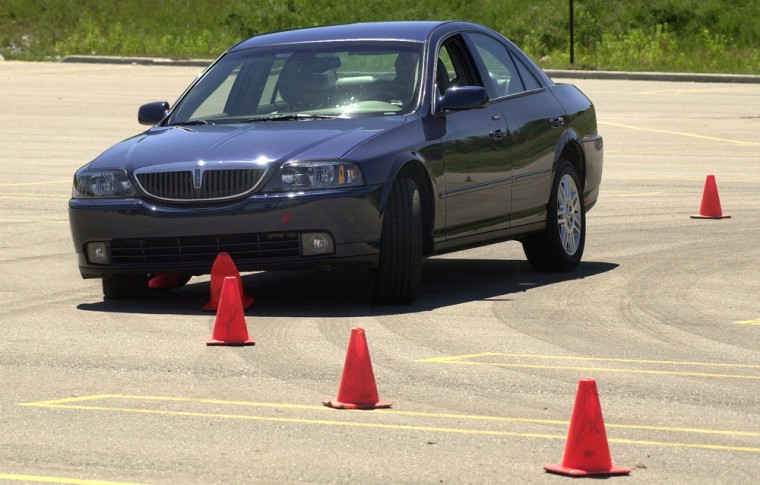 A test vehicle with its electronic stability control turned off slides over cones during a test in Auburn Hills, Mich. The government, impressed by the promise of anti-rollover technology, is planning to require automakers to include such devices on all new vehicles in the coming years. 