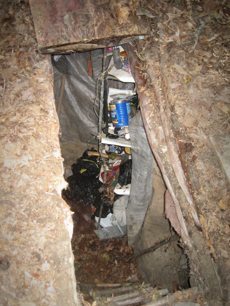 The trap door leading to a hand dug bunker near Lugoff, S.C., is shown Saturday, Sept. 16, 2006. A text message sent by a missing 14-year-old girl to her mother's cell phone led police to the bunker where she was found Saturday in a wooded area near her home. Kershaw County Sheriff Steve McCaskill describes it as one of four so-called bunkers on property. Inside there were shelves made from branches lashed together, a camp stove and a battery that powered a light. (AP Photo/Jim Davenport)