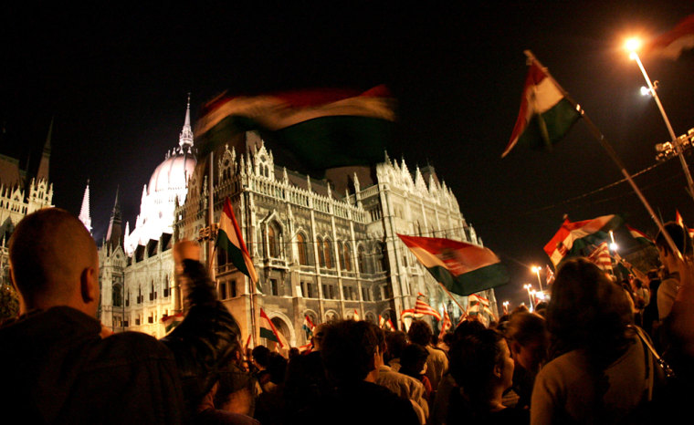 Protesters wave flags as they stand in front of the Hungarian parliament in Budapest