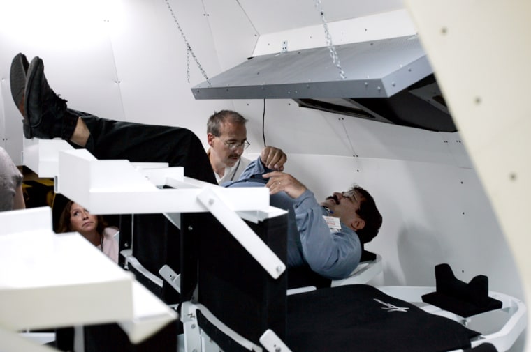 AP reporter Seth Borenstein, right, gets situated in the mockup of the Orion spacecraft with the help of Lockheed Martin engineer Marc Sommers.