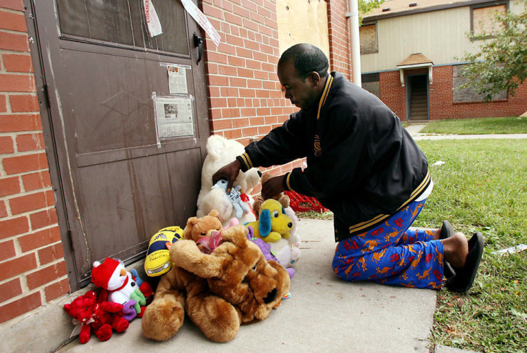 Shawn Crawford places stuffed animals in front of an apartment in the John DeShields public housing complex Sunday in East St. Louis, Ill., near where three children were found murdered Saturday. 