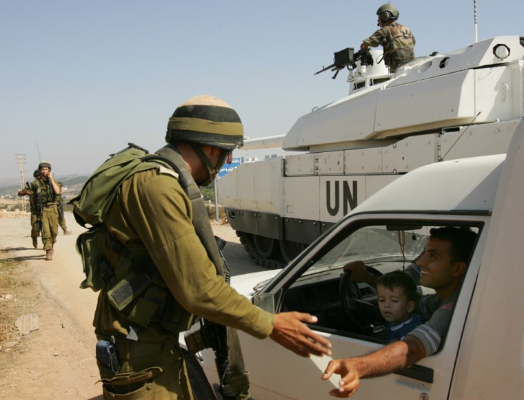 An Israeli soldier checks the papers of a Lebanese man after French U.N. peacekeepers, rear, blocked an Israeli convoy from penetrating deeper into Lebanese territory near the southern village of Marwaheen, Lebanon, on Thursday.