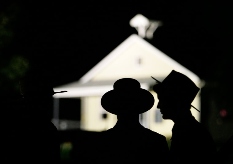 Amish men are seen in front of the schoolhouse where a gunman shot several students and himself in Nickel Mines, Pa., on Monday.