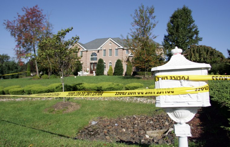 Police tape secures a home, the scene of a shooting, in Manalapan, N.J., on Sunday. Authorities say Alim Hodzic of Manalapan shot and killed 41-year-old Esat Astafovic and his 35-year-old wife, Violsa, late Saturday at their home in the affluent section of Monmouth County. 