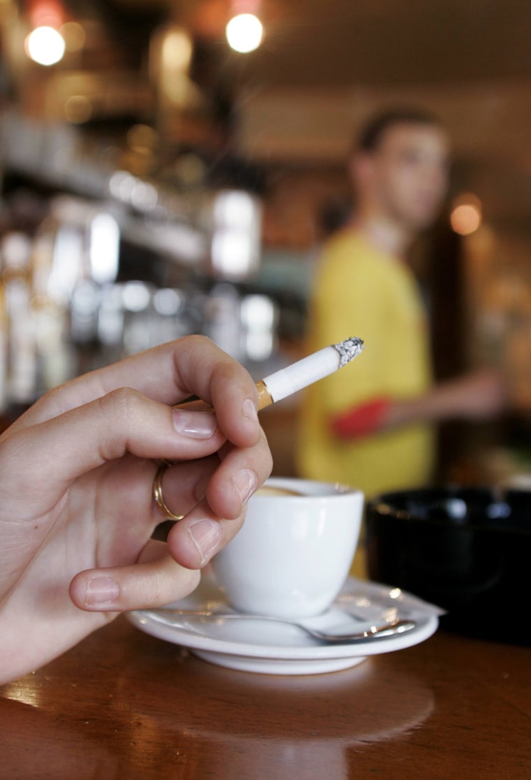 Woman smokes a cigarette in a Paris cafe during her coffee break