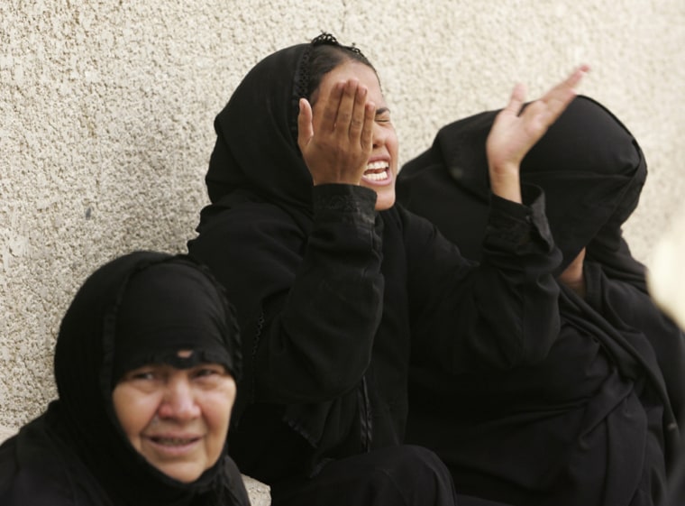Women cry while waiting to claim the bodies of two relatives killed on Sunday night's mortar attack in Baghdad