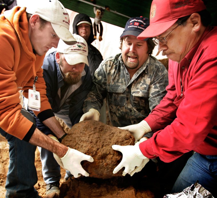 Houston Museum of Natural Science workers Chris Flis (far left), Andy Smith (second from left), Johnny Castillo (right) and meteor hunter Steve Arnold (center) lift a meteorite found in a field near Greensburg, Kan. 