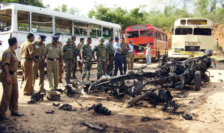 Officials surround the wreckage of a truck that exploded in a suicide attack near Dambulla, about 90 miles northeast of Colombo, Sri Lanka on Monday.