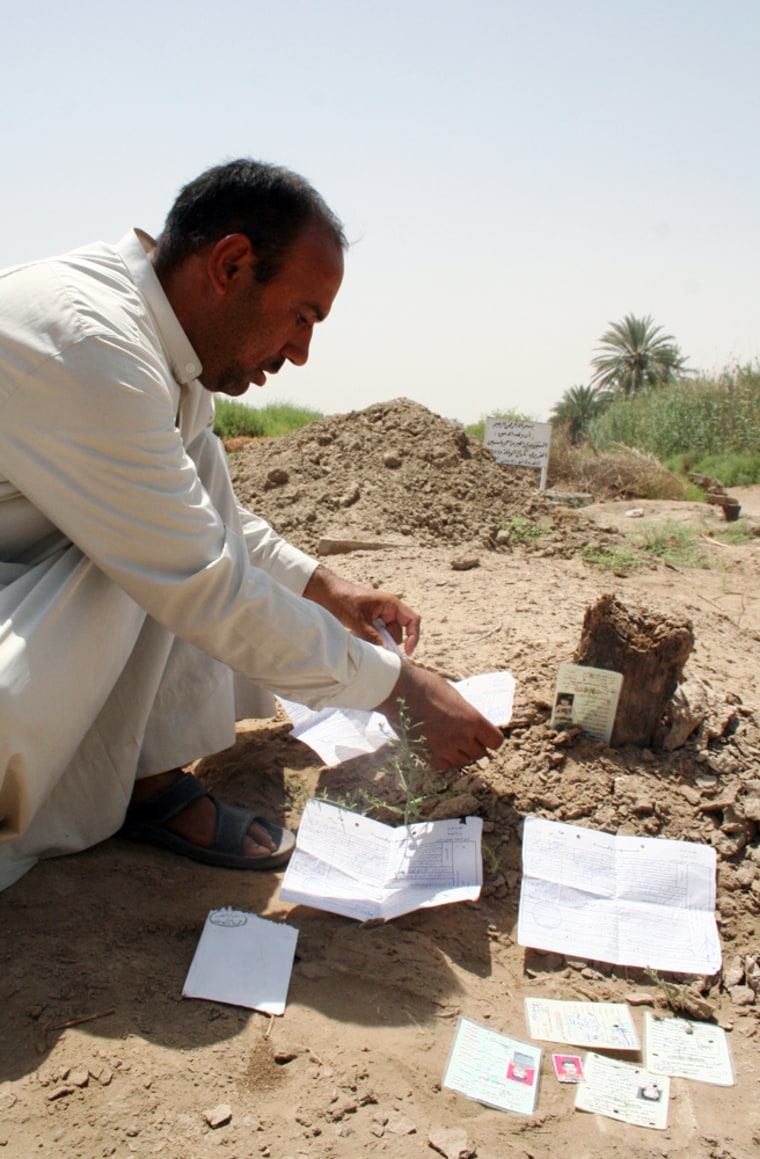 Mohammed al-Janabi, uncle of the girl allegedly raped and killed by U.S. soldiers, displays death certificates and IDs on his niece's grave in Mahmoudiya, north of Baghdad, on Thursday.
