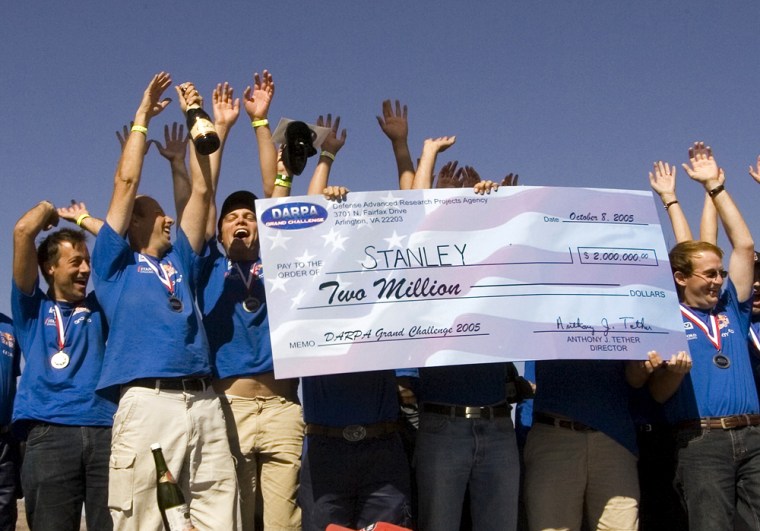 Stanford Racing Team's members hold a $2-million dollar check, after their unmanned vehicle Stanley, a tricked-out Volkswagen Touareg R5 was declared the official winner of the DARPA Grand Challenge 2005 in Primm, Nevada, in October 2005. The Pentagon's research arm, which has hosted the high-tech contests since 2004, blames an obscure law signed by President Bush this week that it claims prevents it from awarding the $2.7 million prize money.