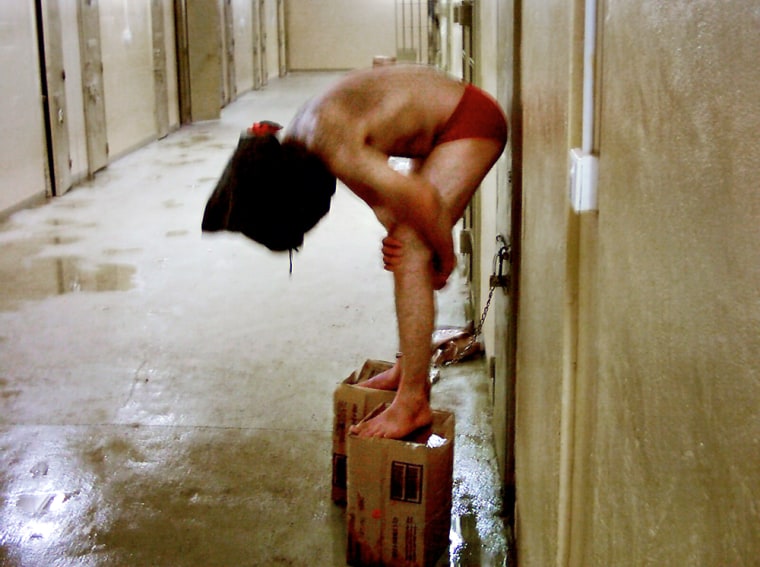 Slug: NA/PICTURES   Date:  unknown    Photo:  MANDATORY CREDIT TO THE WASHINGTON POST   Location:  Abu Ghraib Prison on the outskirts of Baghdad, Iraq  Caption:  In this undated still photo, a hooded Iraqi detainee appears to be cuffed by the ankle to a door handle and made to balance two boxes at the Abu Ghraib Prison.   **MANDATORY CREDIT TO THE WASHINGTON POST**INTERNET OUT**NO SALES** ------------> RECEIVED PERMISSION FROM MICHAEL DUCILLE THAT WE CAN USE THE IMAGES <-----------