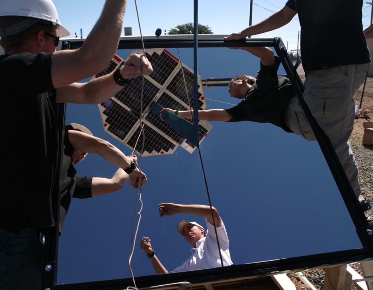 University of Saskatchewan Space Design Team members adjust their beam-powered climber, seen here reflected in a mirror, before a final attempt to have the device ascend a tether on Sunday. The climber stopped several feet up, apparently because the reflected beams of light went off target at the wrong time.