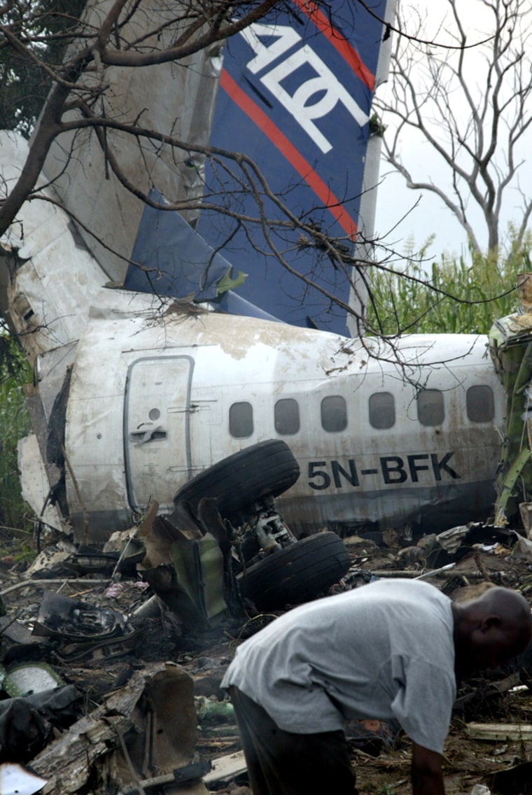 A man sifts through the wreckage of a Nigerian airliner in a field in Abuja, Nigeria, on Sunday. At least 96 passengers were killed in Sunday's crash.