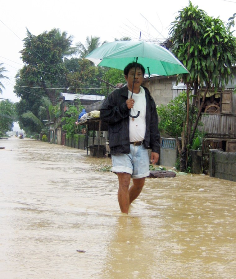 A man wades through a flooded portion of a highway following heavy rains brought about by Typhoon Cimaron on Monday, in Isabela province in northern Philippines. 