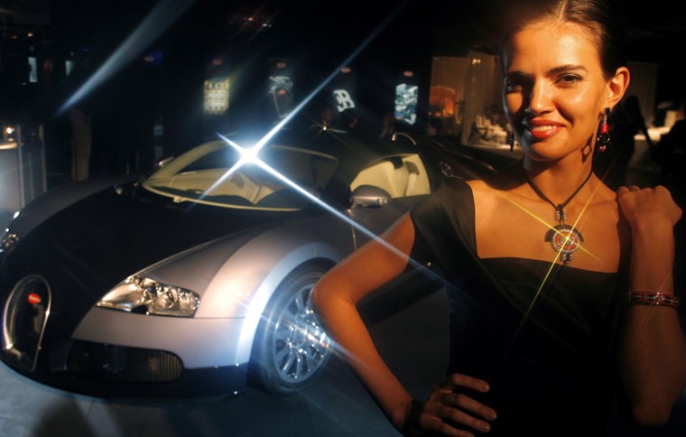 A Russian model displays $1.2 million Buggati jewelry and a $1.3 million Bugatti car at Millionaire Fair in Moscow. The fair is a festival of super-luxury goods offering lavish consumer goods to the Russian capital.