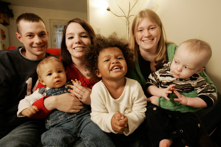 Jenna Hatfield, center back, holds her 1-year-old son Nicholas, while her biological daughter Ariana, center front, smiles, at her home on Friday, Nov. 17 in Cambridge, Ohio. At left is Hatfield's husband, Joey and next to Ariana, right, is her adoptive mother Denise Loss and Loss's son, Joey, 1. 