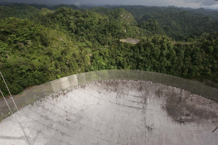 An aerial view hundreds of feet above the dish of the world's largest radio telescope, at the National Astronomy and Ionosphere Center, in Arecibo, Puerto Rico, Nov. 16, 2006. Astronomers here searching for asteroids on a collision course with Earth are bracing for a more worldly threat: The steepest budget cuts and first layoffs since the observatory opened in 1963. (AP Photo/Brennan Linsley)
