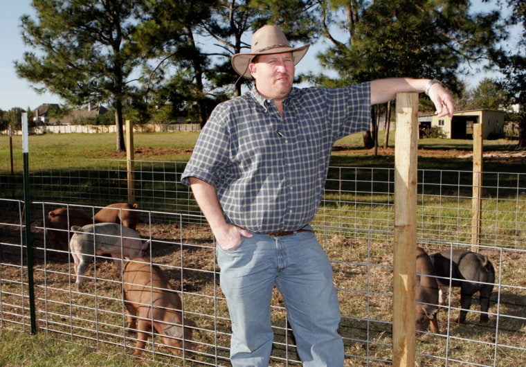 Craig Baker poses beside his pigs outside his Katy, Texas, business, on Monday. Baker has threatened to race pigs on the edge of his property on the Muslim holy day, in response to a Katy Islamic Association plan to build a mosque near his property. 