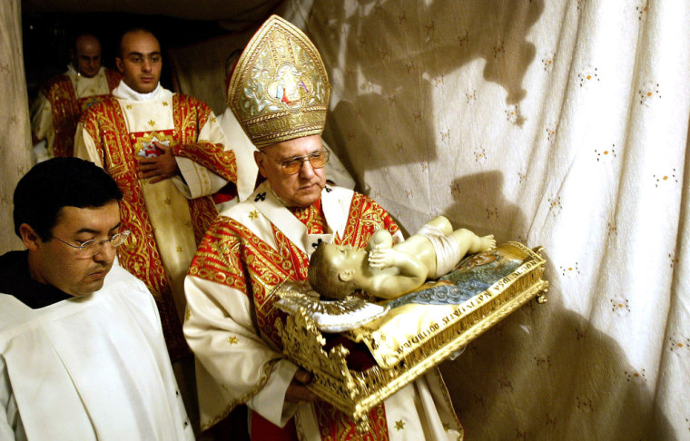 The Latin Patriarch of Jerusalem Michel Sabbah carries a statue of Baby Jesus down into the grotto, the site where Christians believe Jesus Christ was born, following the Catholic Christmas Midnight Mass at the Church of the Nativity in the West Bank town of Bethlehem Dec. 25, 2004. 