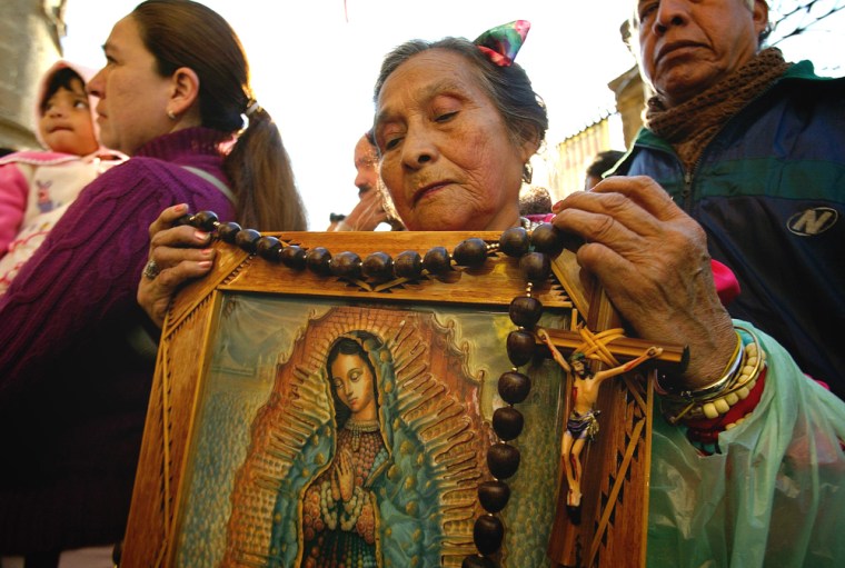 A woman carries the image of the Virgin of Guadalupe as she lines up to enter the basilica during the Day of the Virgin of Guadalupe on Tuesday.