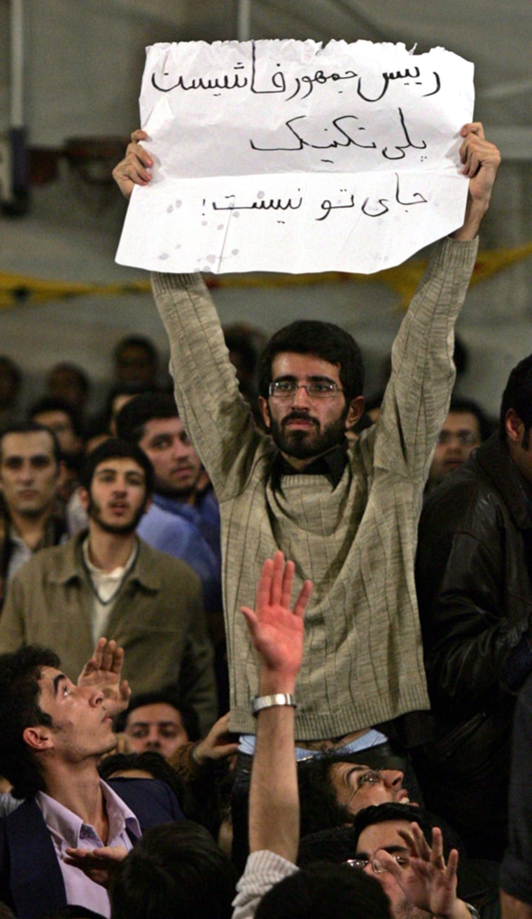 Iranian students stage a rare demonstration against President Mahmoud Ahmadinejad on Monday, lighting a firecracker and burning his photograph in the audience as he delivered a speech at the Amir Kabir Technical University in Tehran on Monday, the state news agency said. The student seen here holds a placard ,reading: "Fascist president, Polytechnich is not your place.”